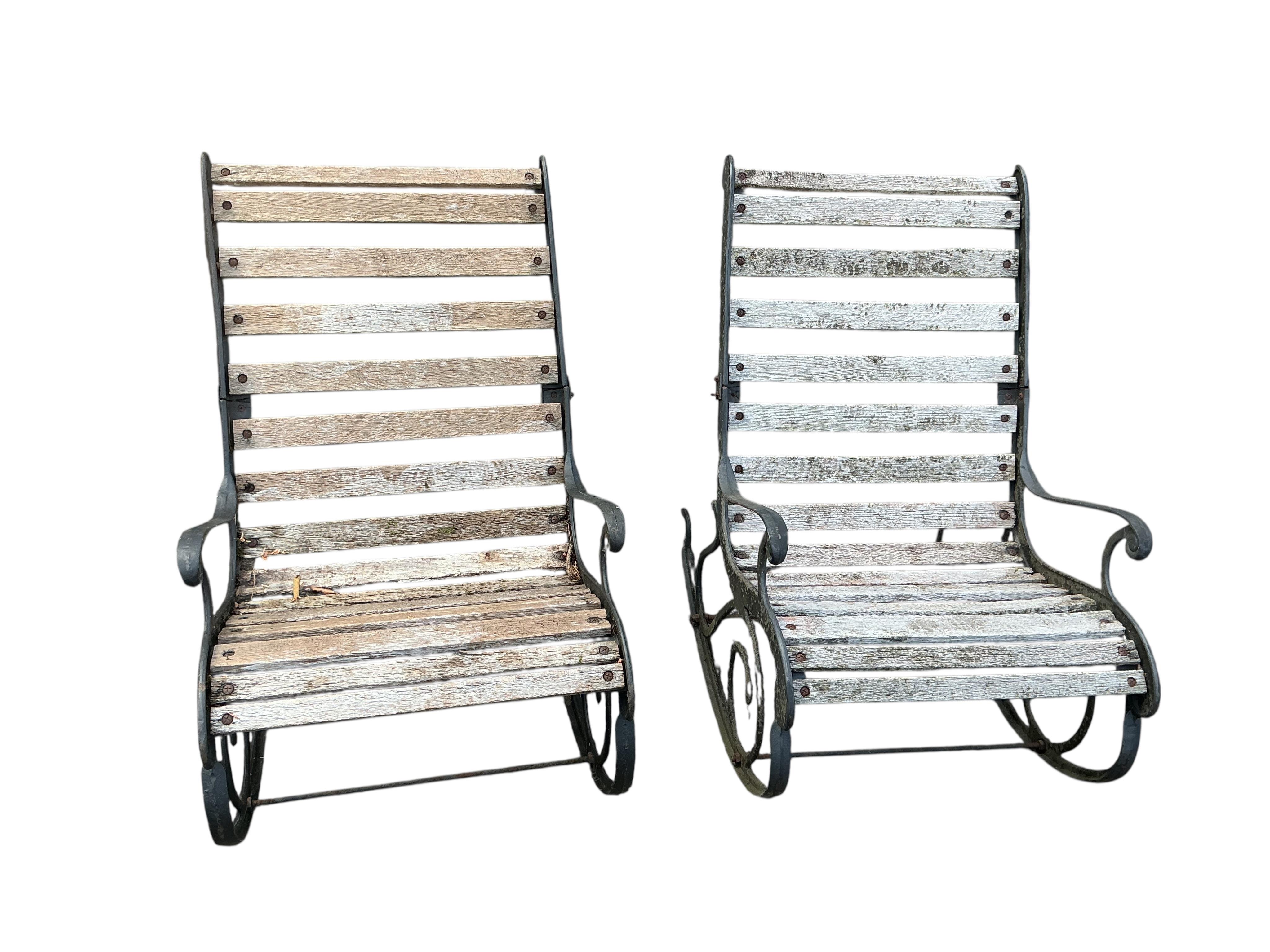 A pair of slatted cast metal garden rocking chairs
